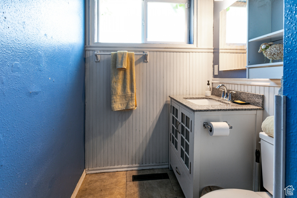 Half bath featuring a sink, baseboards, toilet, and wainscoting