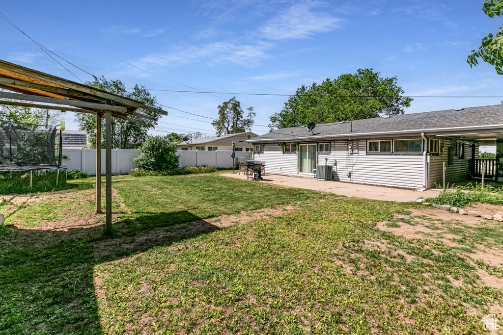 View of yard featuring a trampoline, a patio area, and central air condition unit