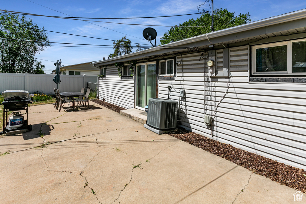 View of patio with central AC, outdoor dining space, area for grilling, and fence