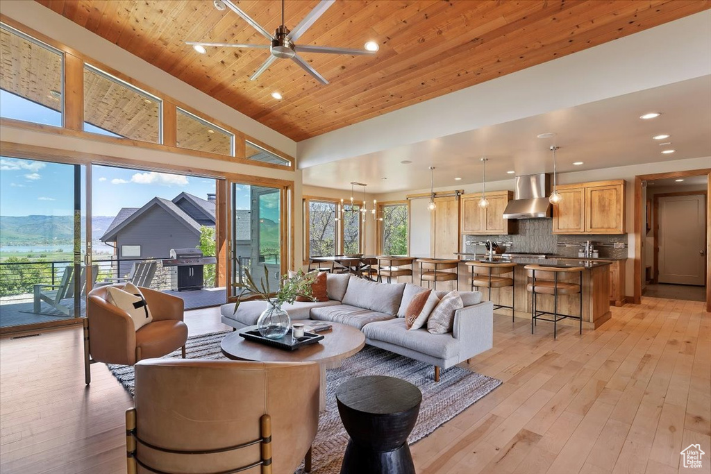 Living area with a towering ceiling, light wood-style floors, recessed lighting, ceiling fan, and wooden ceiling
