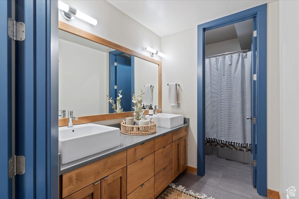 Bathroom with double vanity, tile patterned floors, and baseboards