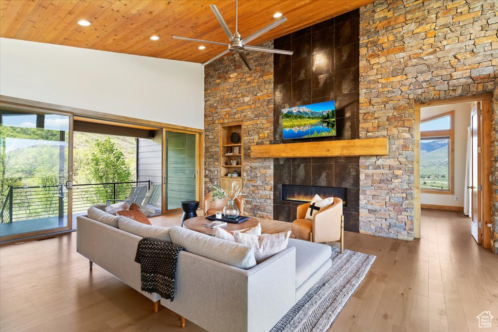 Living area featuring a ceiling fan, built in shelves, a stone fireplace, wood ceiling, and recessed lighting