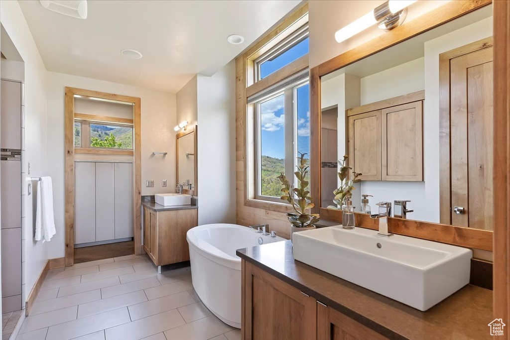 Full bath with a freestanding bath, tile patterned floors, and two vanities