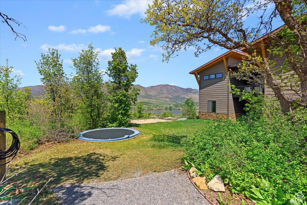 View of green lawn with a trampoline and a water and mountain view