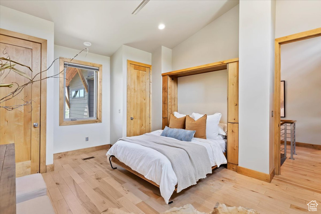 Bedroom with light wood-style flooring, baseboards, and vaulted ceiling