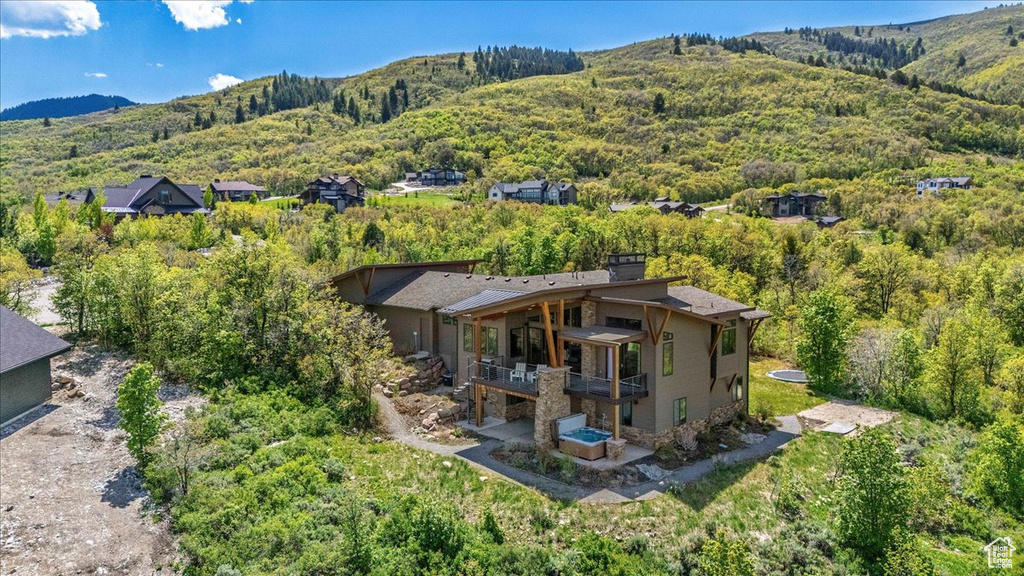View from above of property with a mountain backdrop and a heavily wooded area