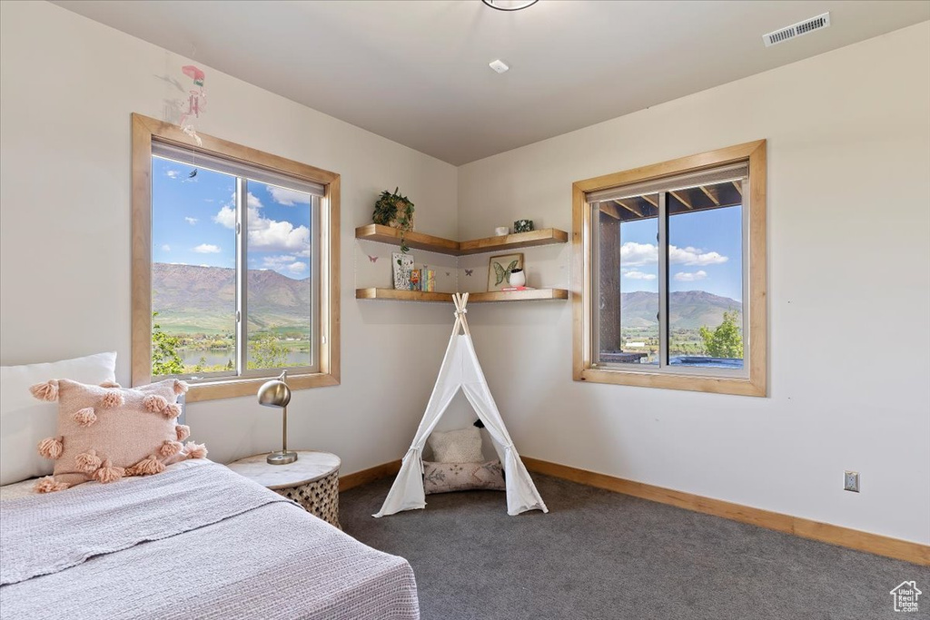 Bedroom featuring multiple windows, carpet, baseboards, and a mountain view