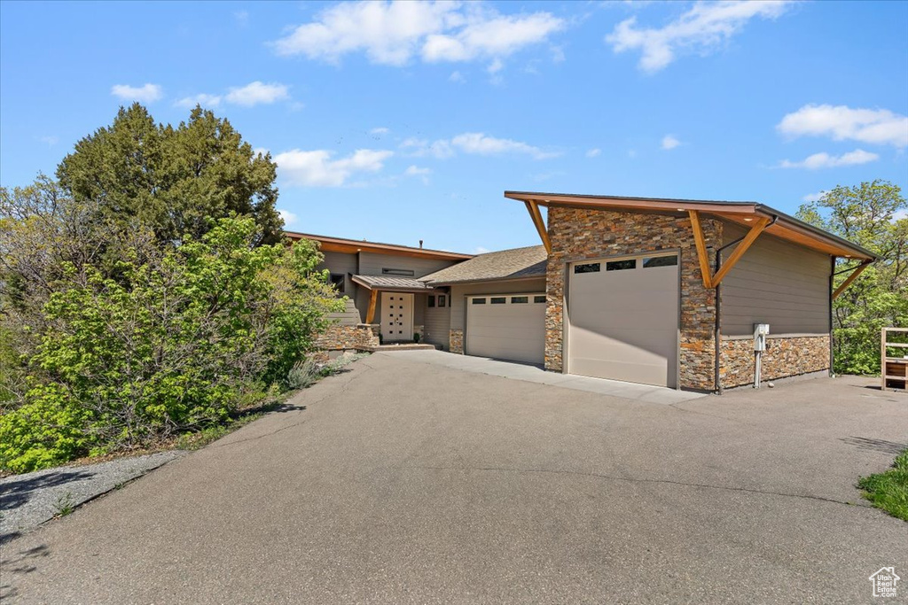 View of front of property with stone siding, a garage, and driveway
