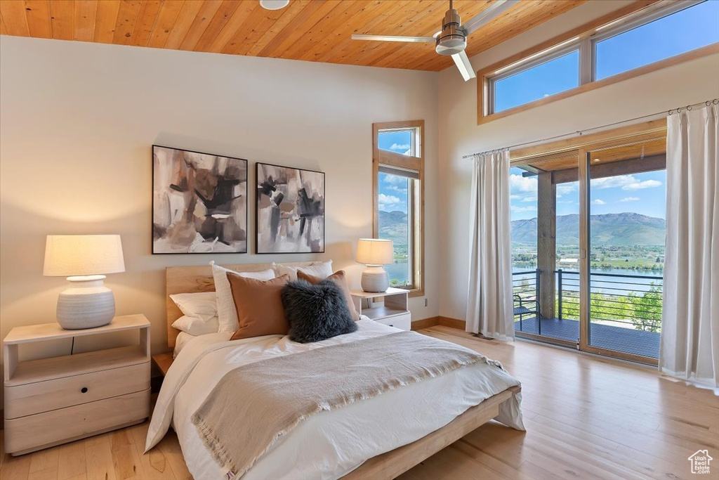 Bedroom with access to outside, wood finished floors, wood ceiling, baseboards, and a water and mountain view