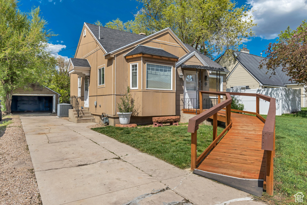 View of front of home featuring a shingled roof, an outdoor structure, a front lawn, and a garage