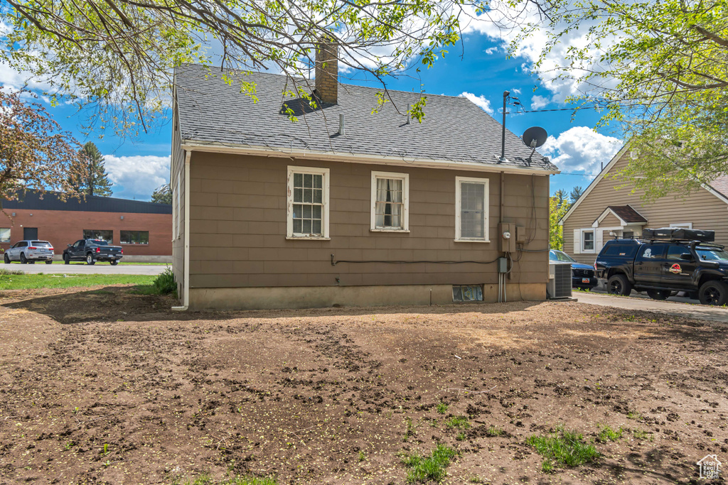 Back of house featuring a chimney and roof with shingles