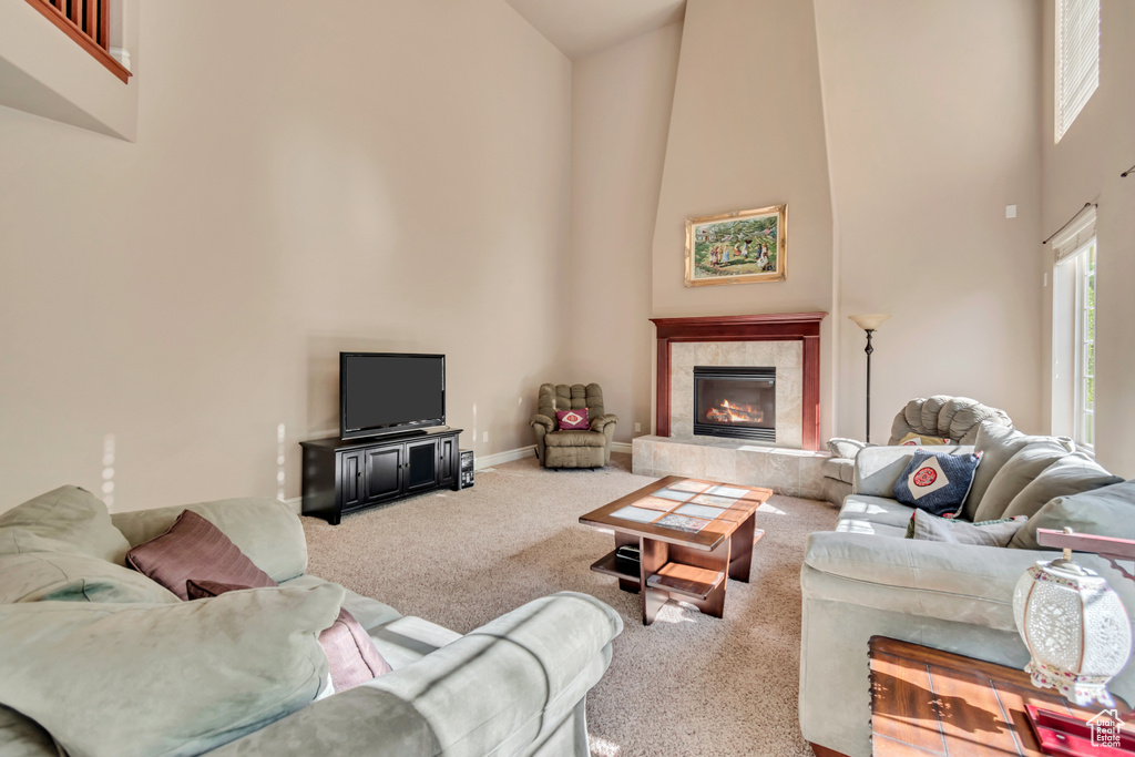 Carpeted living room featuring high vaulted ceiling, a tile fireplace, and baseboards