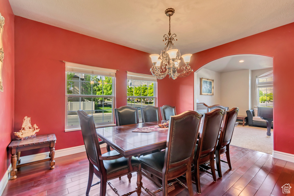 Dining area with arched walkways, dark wood finished floors, a chandelier, and baseboards