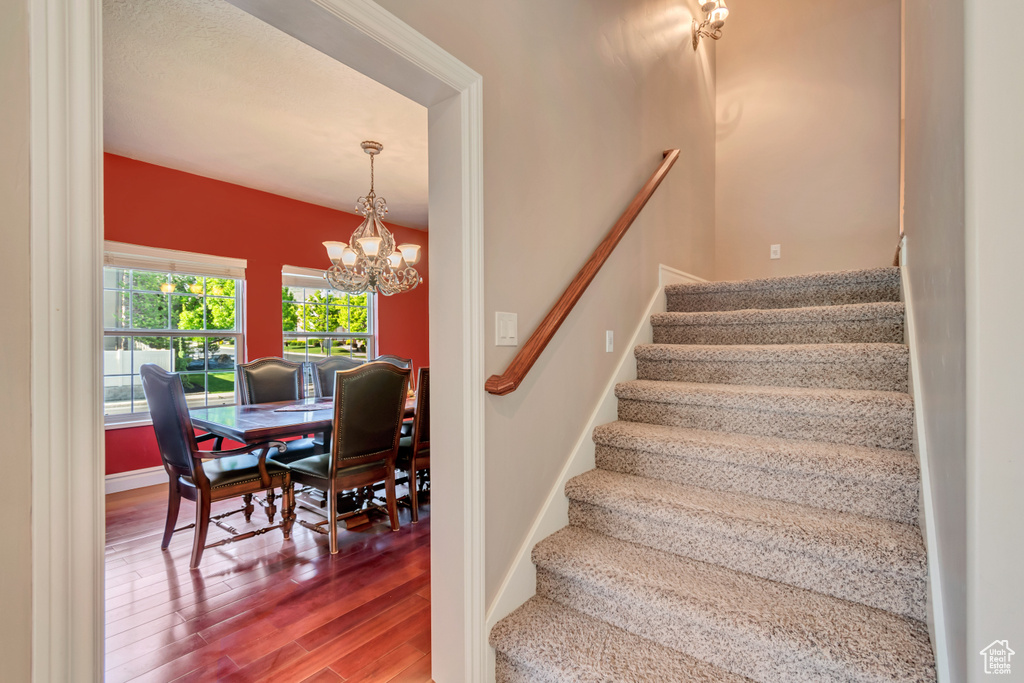 Stairs featuring wood finished floors, a chandelier, and baseboards