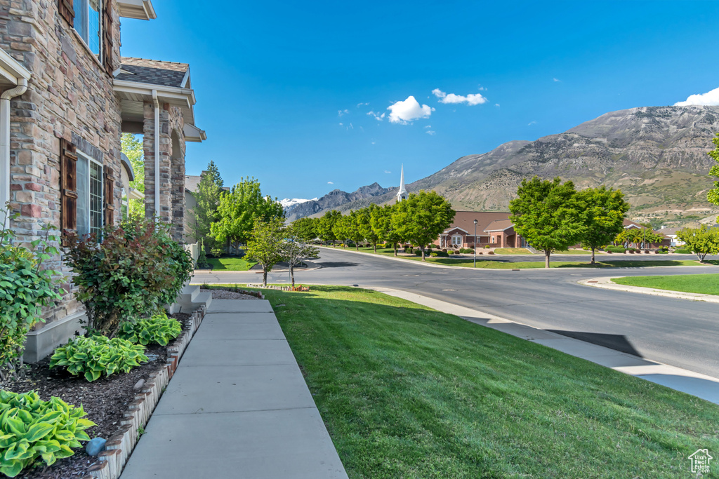 View of asphalt street featuring a mountain view, sidewalks, and curbs