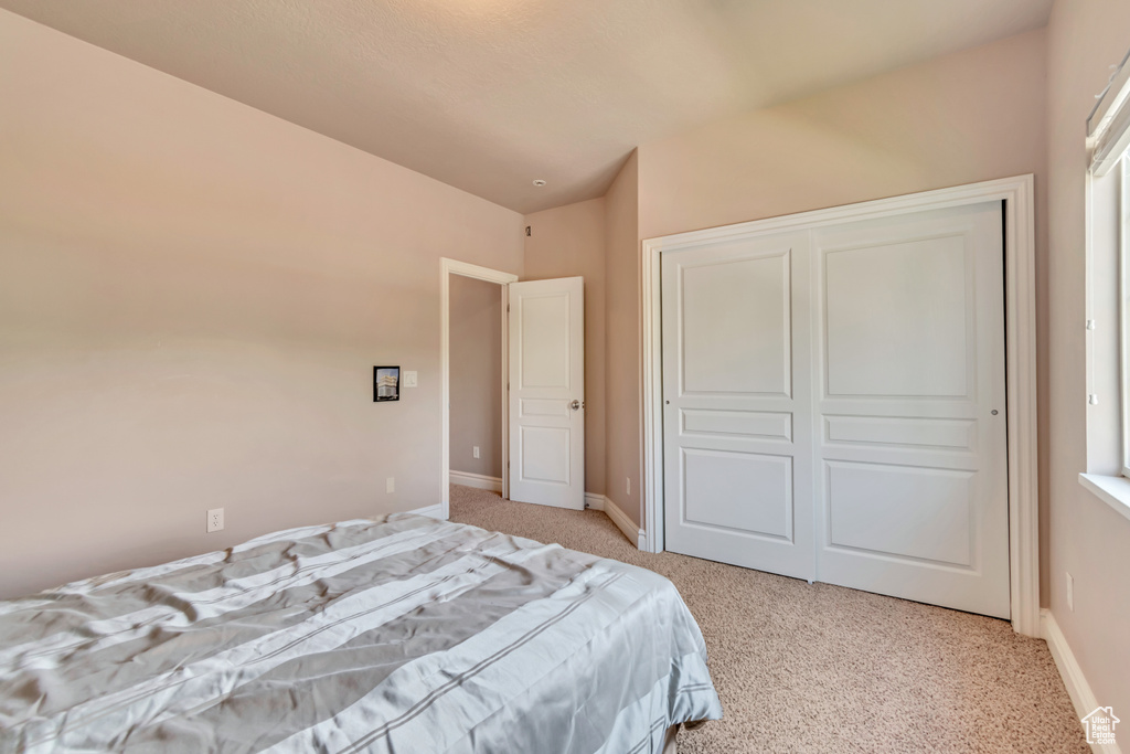Bedroom featuring carpet, vaulted ceiling, baseboards, and a closet