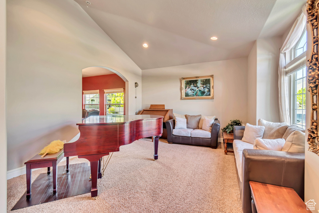 Living area with arched walkways, lofted ceiling, carpet floors, recessed lighting, and baseboards