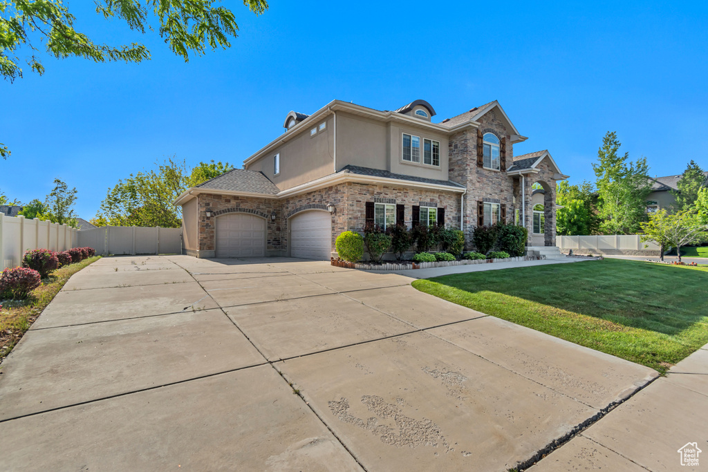 View of front of property with stucco siding, concrete driveway, an attached garage, and stone siding