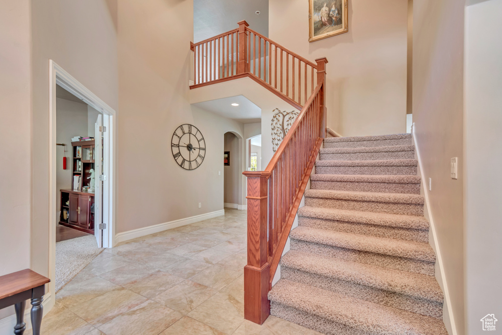 Stairway with arched walkways, a towering ceiling, and baseboards