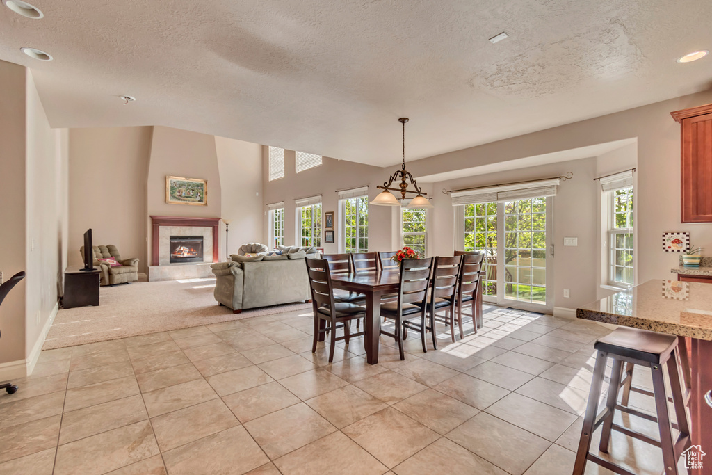 Dining area with a textured ceiling, light tile patterned floors, baseboards, a fireplace, and light carpet