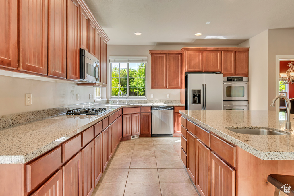 Kitchen featuring stainless steel appliances, a sink, light stone counters, recessed lighting, and light tile patterned floors