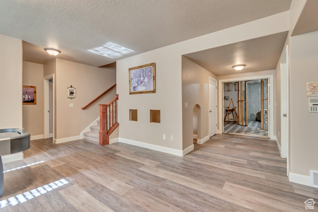 Entrance foyer featuring light wood-style floors, stairs, a textured ceiling, and baseboards