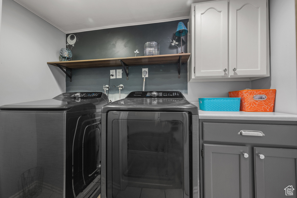Laundry area featuring separate washer and dryer, cabinet space, and crown molding