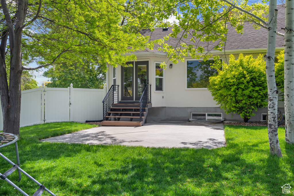Entrance to property with a gate, a patio, a shingled roof, and stucco siding