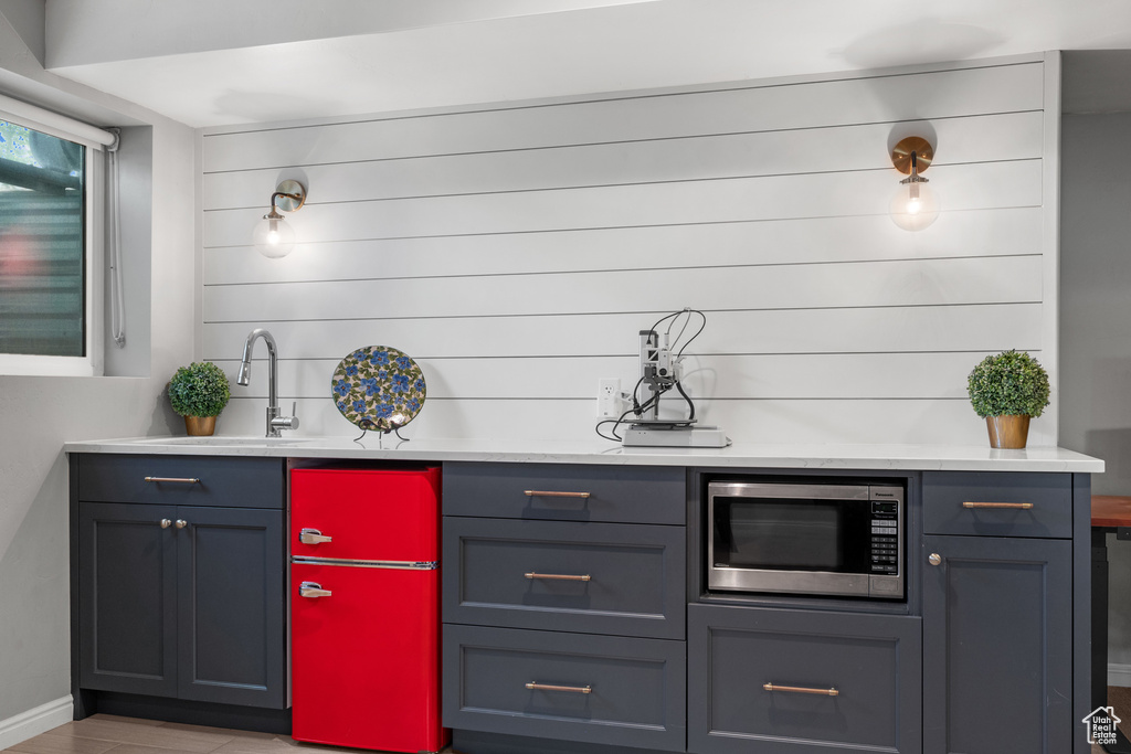 Bar area with stainless steel microwave, a sink, baseboards, and wood finished floors