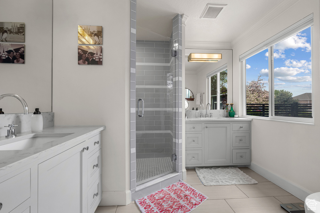 Full bathroom featuring a shower stall, crown molding, two vanities, tile patterned floors, and baseboards