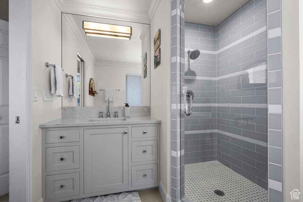 Full bathroom featuring ornamental molding, tiled shower, and vanity