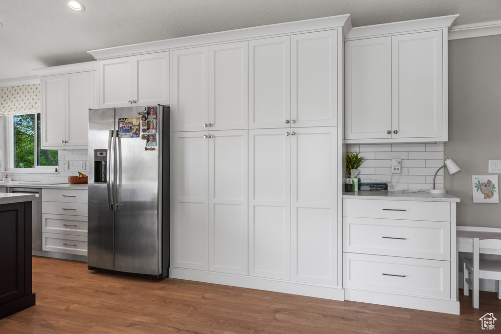 Kitchen with stainless steel refrigerator with ice dispenser, light countertops, tasteful backsplash, and recessed lighting