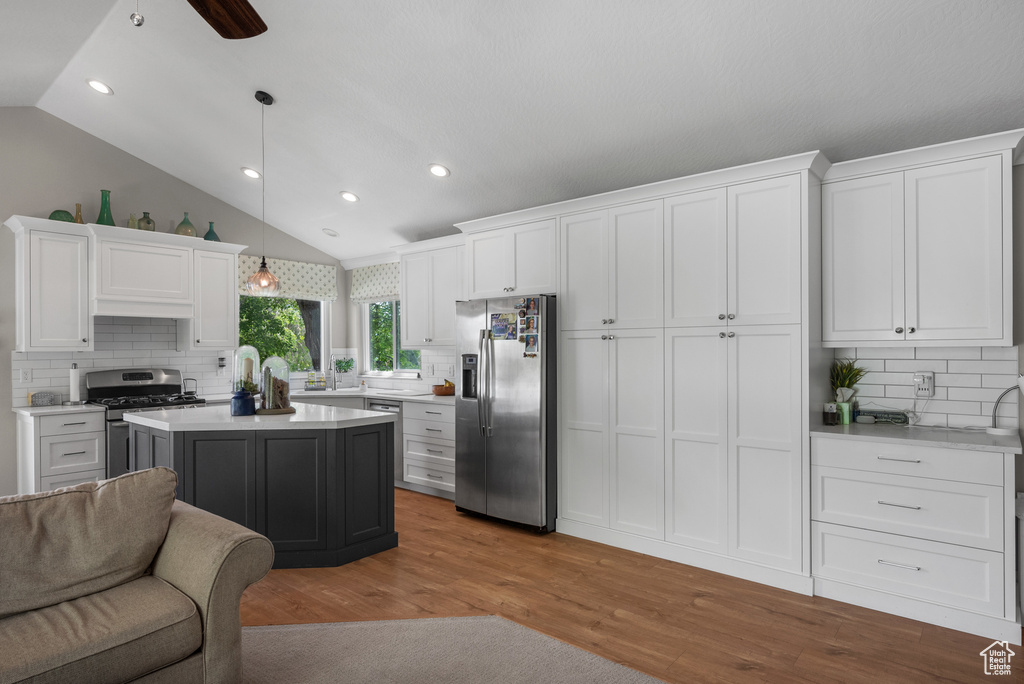 Kitchen with appliances with stainless steel finishes, white cabinetry, decorative backsplash, lofted ceiling, and recessed lighting