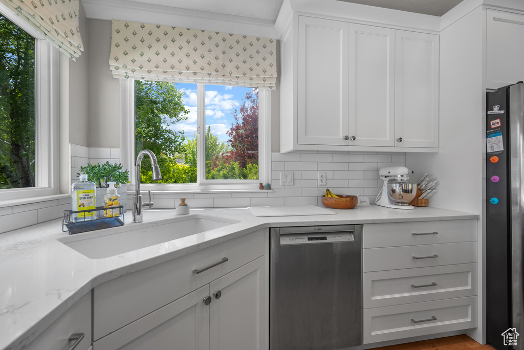 Kitchen with appliances with stainless steel finishes, a sink, healthy amount of natural light, and tasteful backsplash