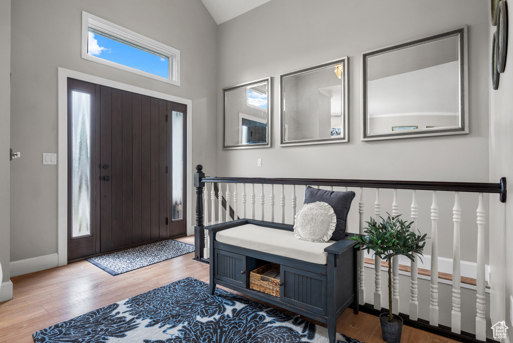 Foyer entrance with wood finished floors, vaulted ceiling, and baseboards