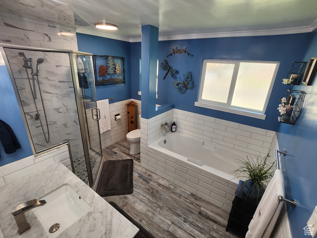 Bathroom featuring a sink, wood finished floors, a bath, ornamental molding, and a stall shower