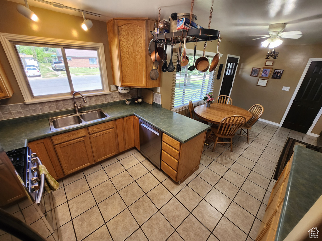 Kitchen featuring a sink, dishwasher, track lighting, light tile patterned floors, and decorative backsplash
