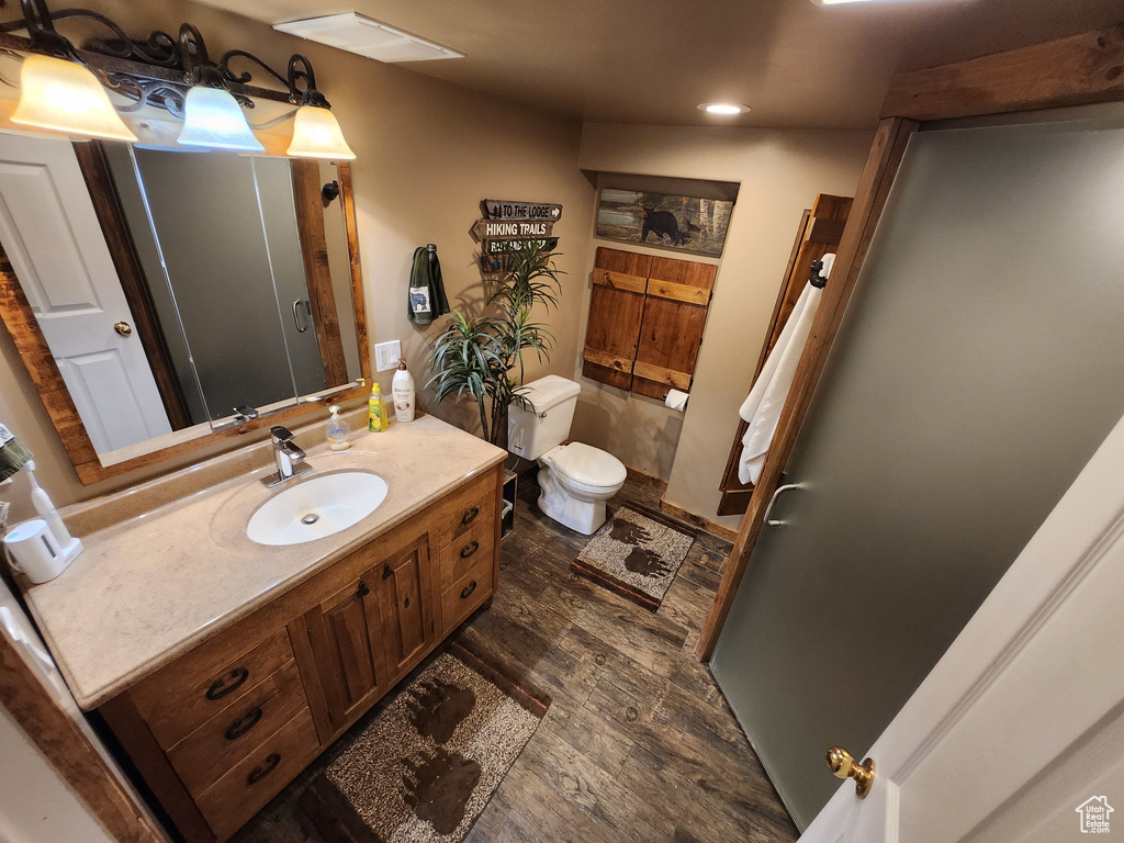 Bathroom with recessed lighting, vanity, wood finished floors, and toilet