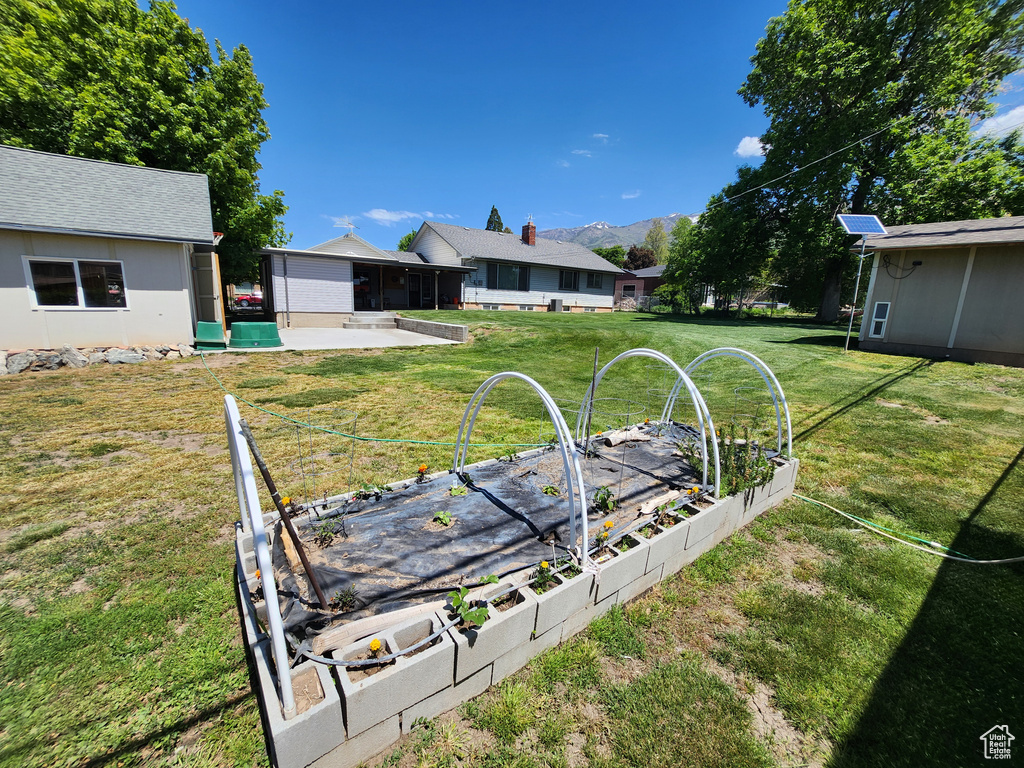 View of grassy yard featuring a vegetable garden and a mountain view