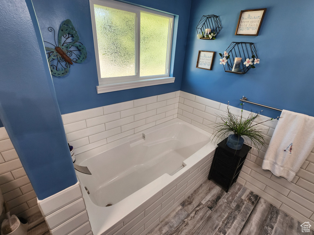 Full bath with a garden tub and wood finished floors