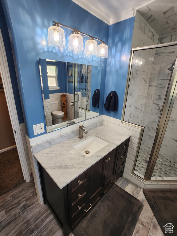 Full bathroom with a stall shower, vanity, wood finished floors, and ornamental molding