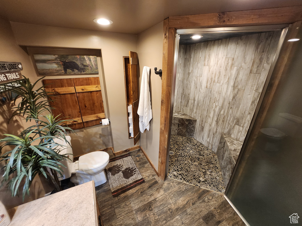 Bathroom featuring a tile shower, recessed lighting, wood finished floors, and toilet