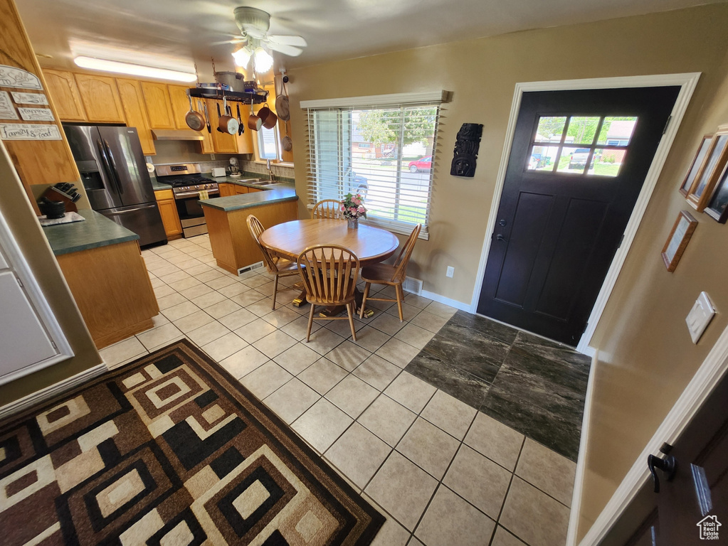 Kitchen with appliances with stainless steel finishes, light tile patterned flooring, plenty of natural light, and under cabinet range hood