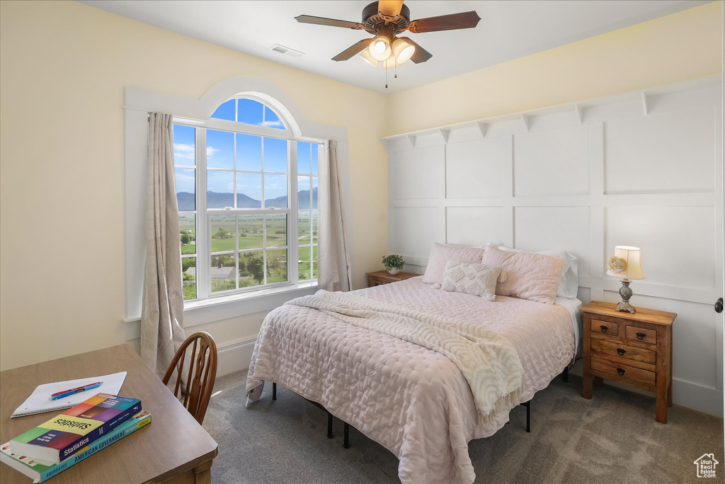Carpeted bedroom featuring multiple windows, a mountain view, and ceiling fan