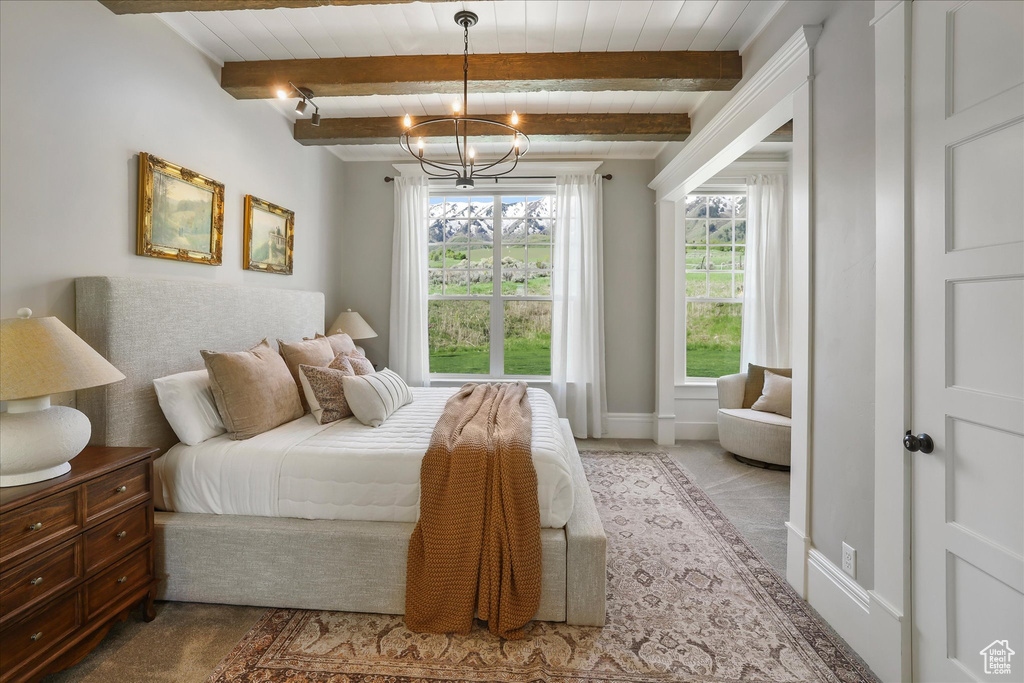 Carpeted bedroom featuring beam ceiling, a chandelier, and baseboards