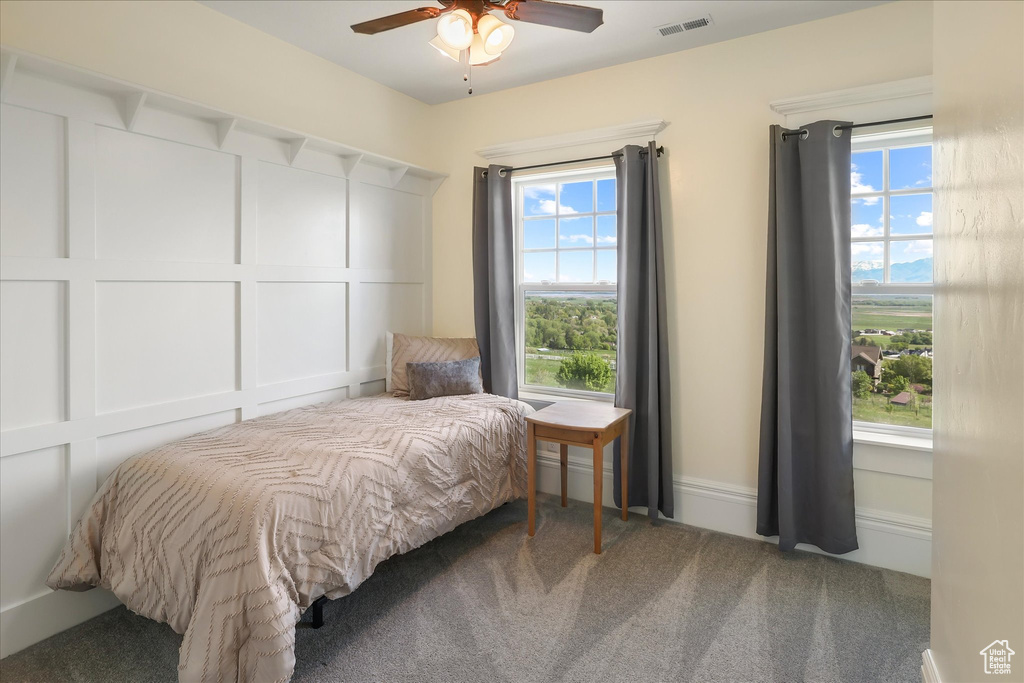 Carpeted bedroom featuring multiple windows and a ceiling fan