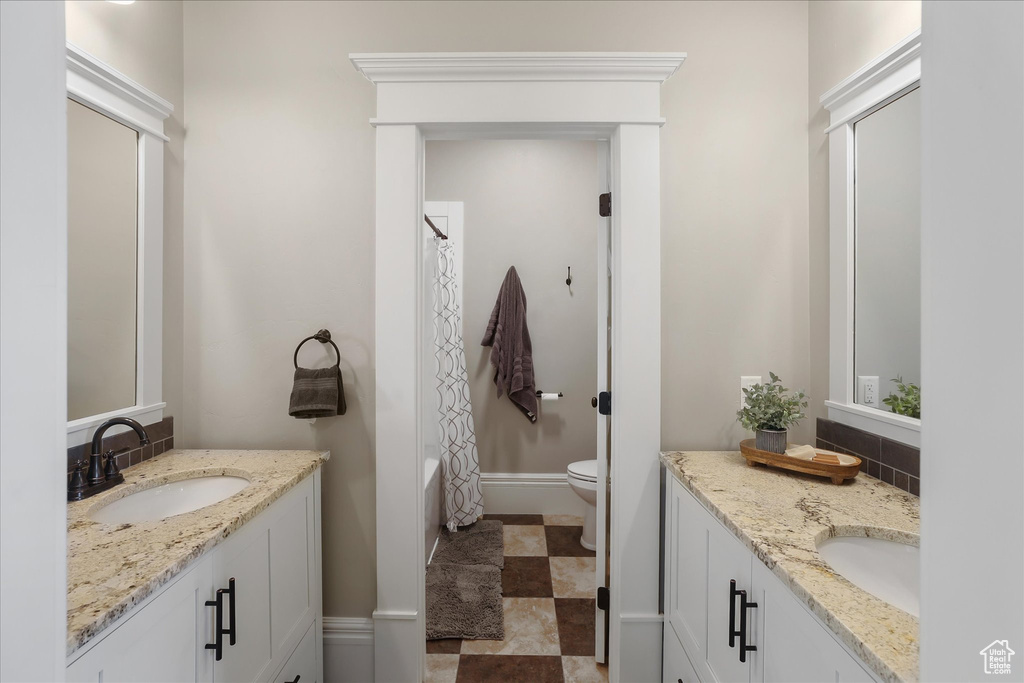Bathroom with two vanities, toilet, shower / tub combo with curtain, and baseboards