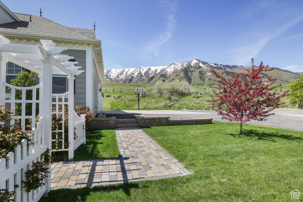 View of grassy yard with a mountain view and a pergola