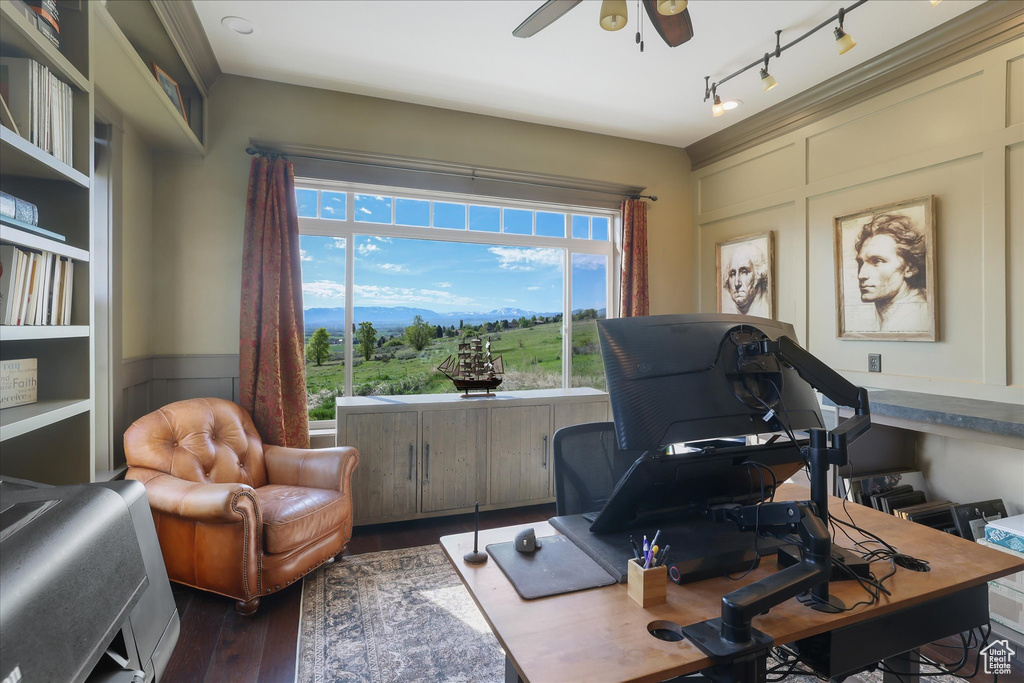 Office space with ceiling fan, wood finished floors, and a decorative wall