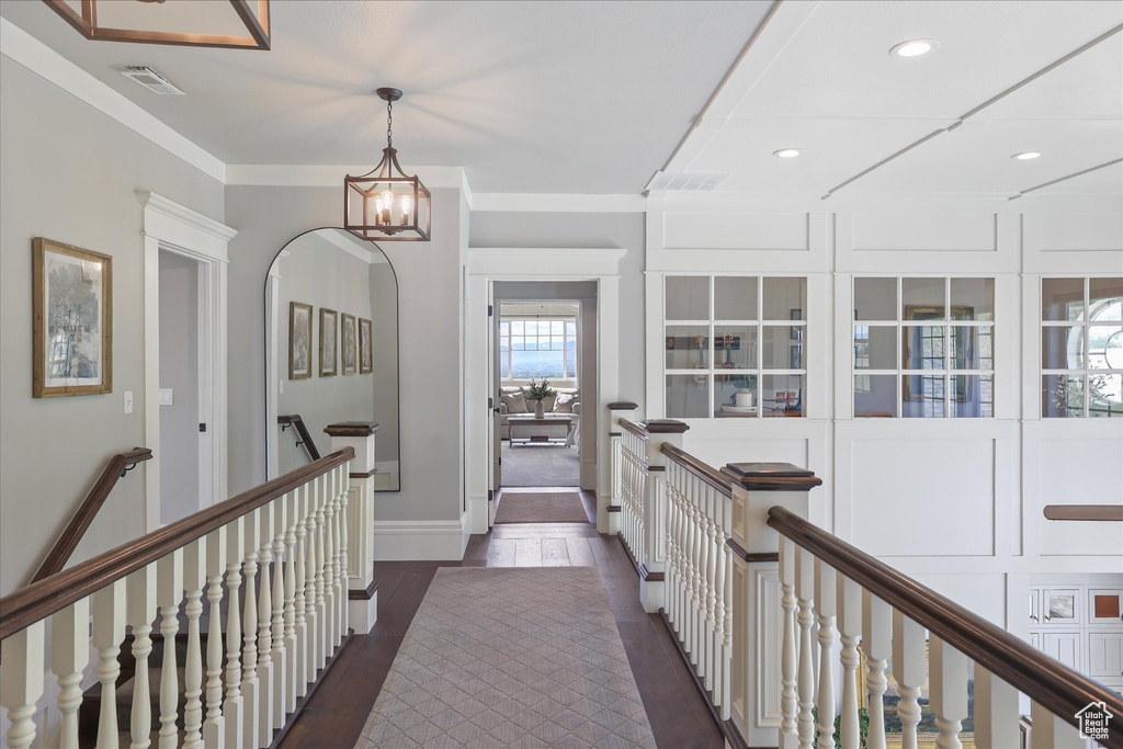 Corridor featuring an upstairs landing, recessed lighting, ornamental molding, dark wood-type flooring, and a chandelier